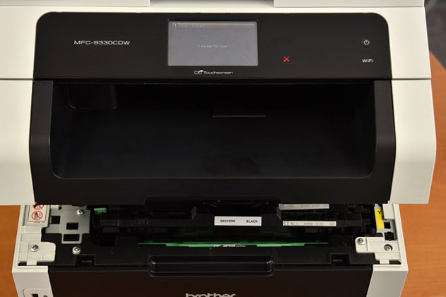 Open the printer lid on your Brother MFC-9340cdw, showing the toner cartridges.